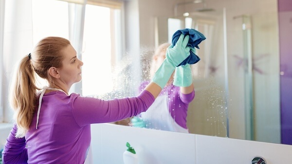 woman cleaning bathroom mirror - www.besthomegear.com