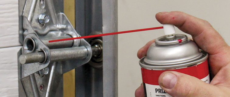 image of lubricating garage door hinge and track