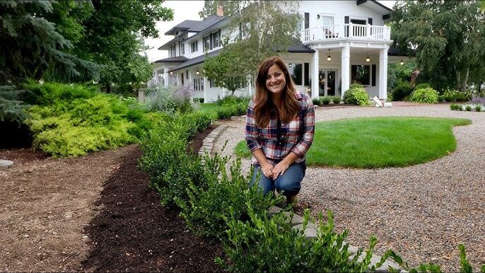 image of woman using organic wood mulch for landscape bed