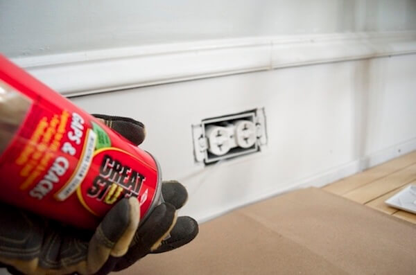 image of someone filling air gaps in electrical outlet with foam sealant